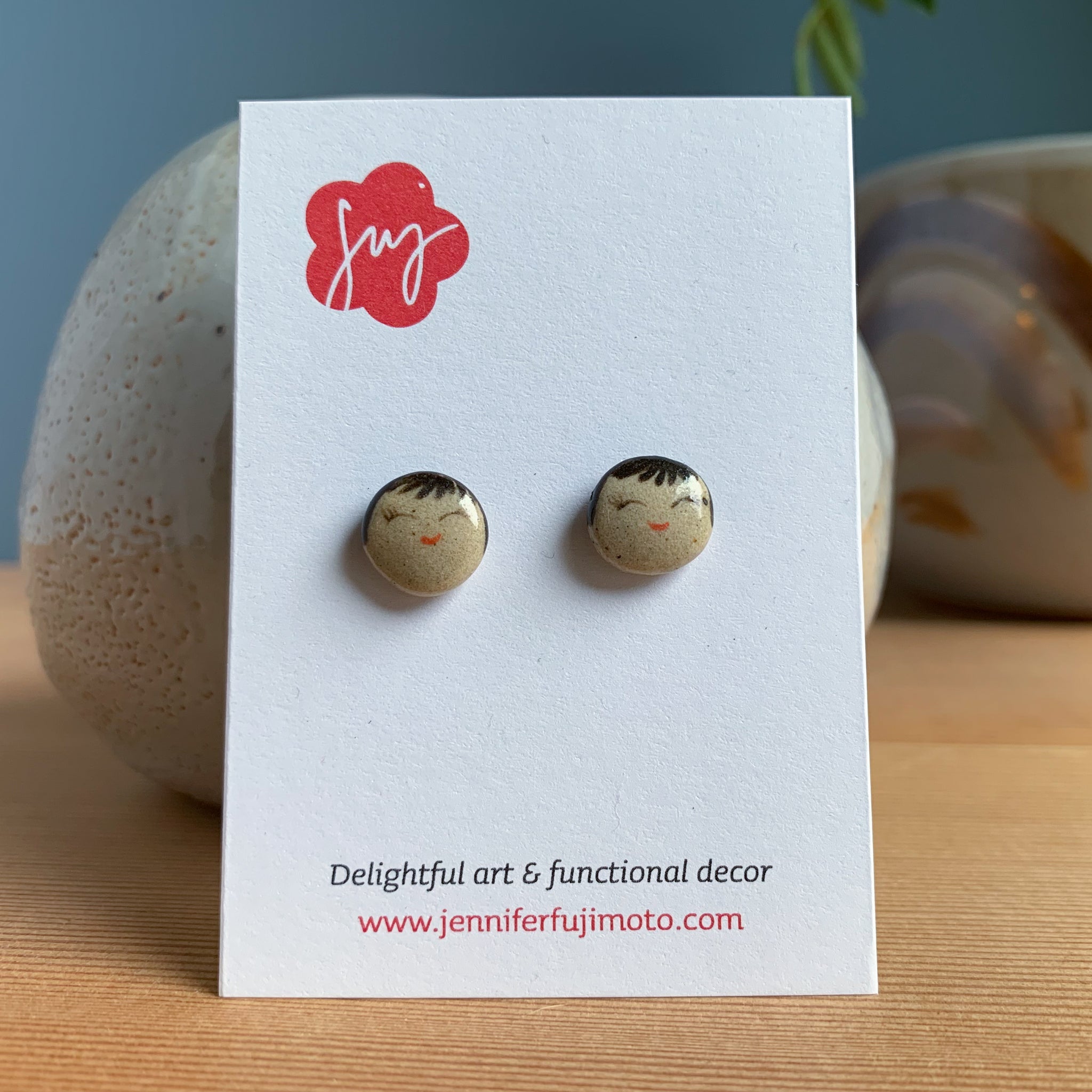Ceramic earrings with cheerful expression on a backing card