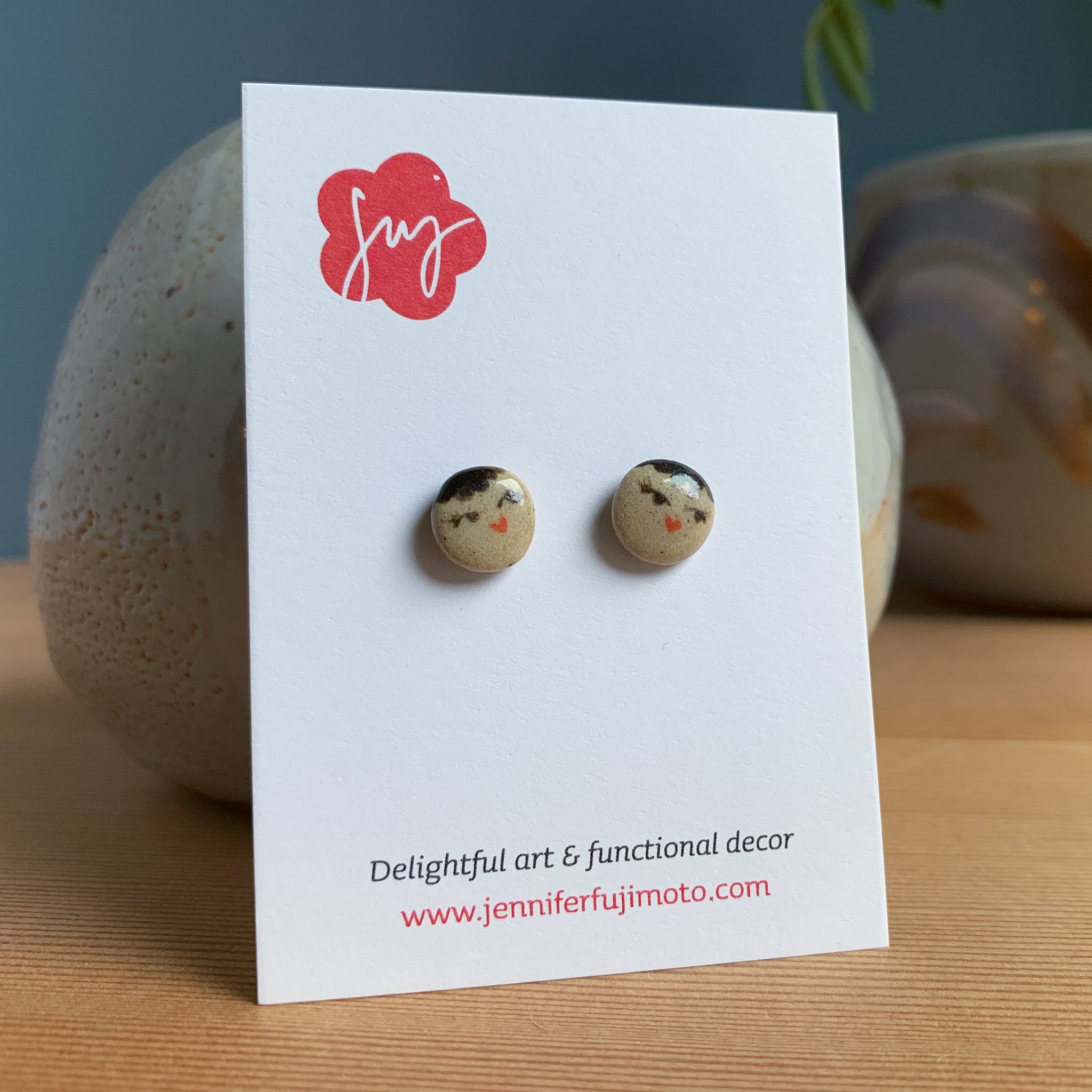 Ceramic earrings with cute coy expression on a backing card